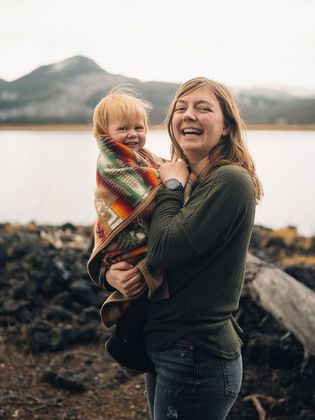 A woman is holding a baby wrapped in a blanket.