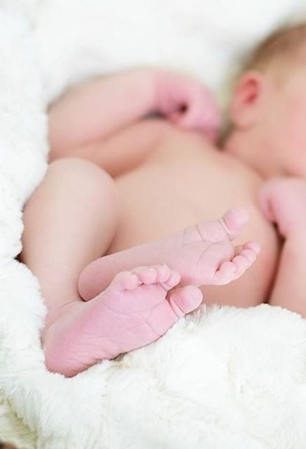 A close up of a baby 's feet on a white blanket.