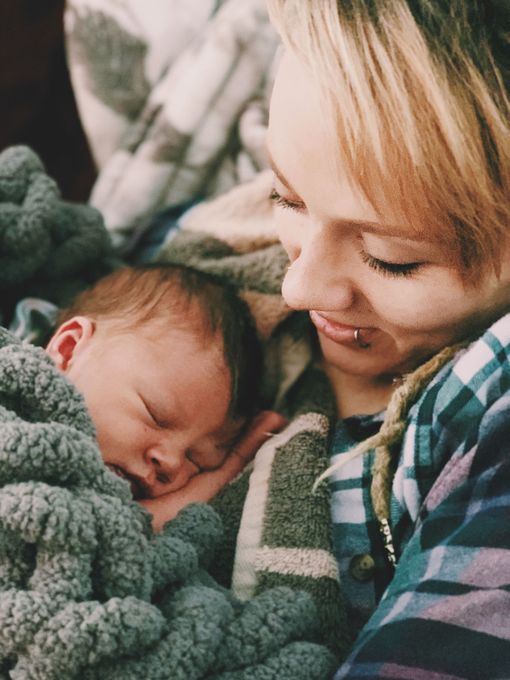 A woman is holding a baby wrapped in a blanket.