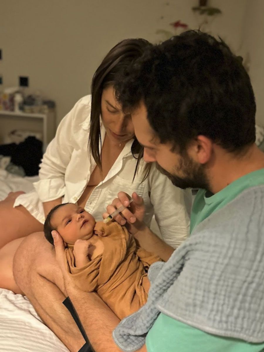 A man and woman are holding a newborn baby on a bed.