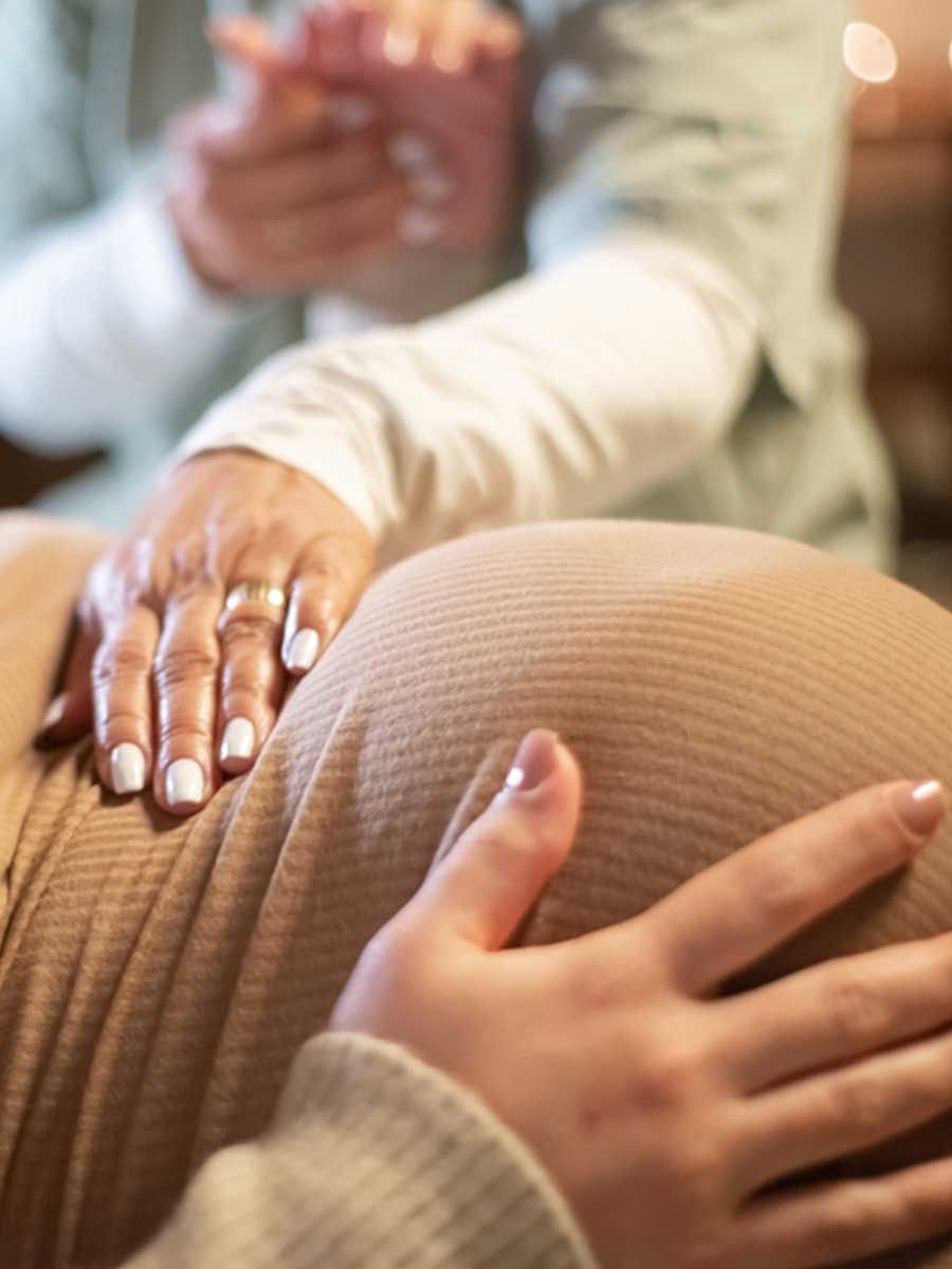 A close up of a person 's hands on a pregnant woman 's belly