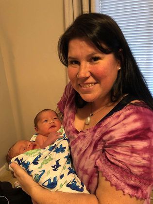 A woman is holding a newborn baby in her arms.