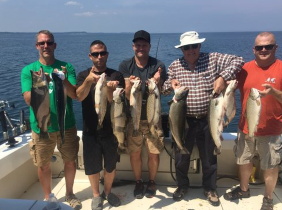 group of people on a boat holding walleye fish