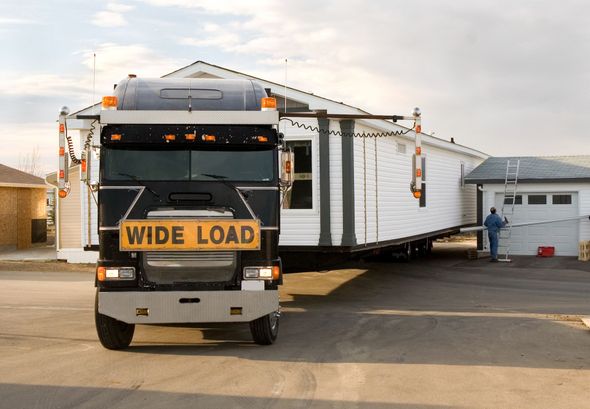 A large truck transporting a prefabricated house labeled 
