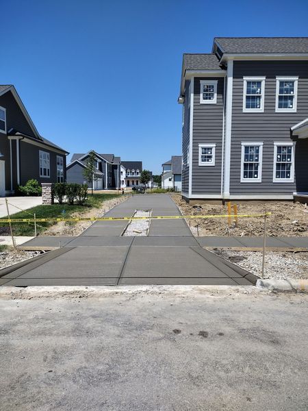 New concrete sidewalk in a residential neighborhood under construction, blue sky.