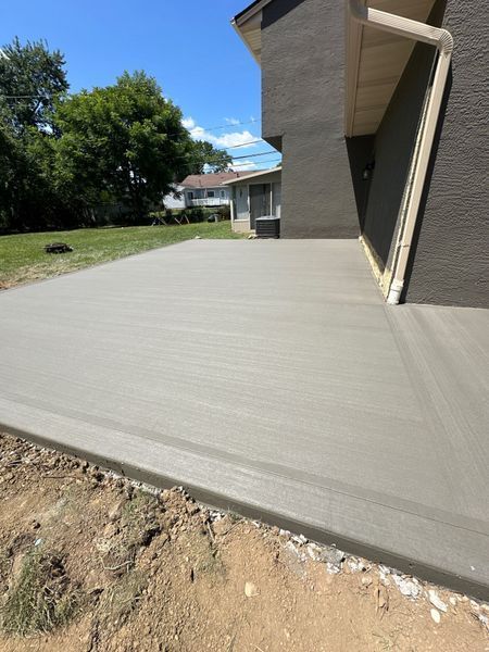 Newly poured concrete patio next to a light gray building.