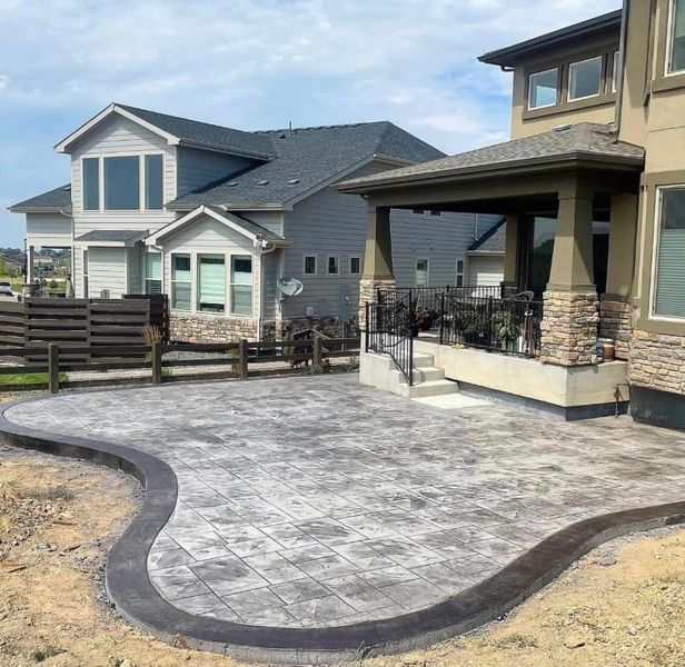 Backyard patio with stamped concrete, a covered porch, and adjacent houses.