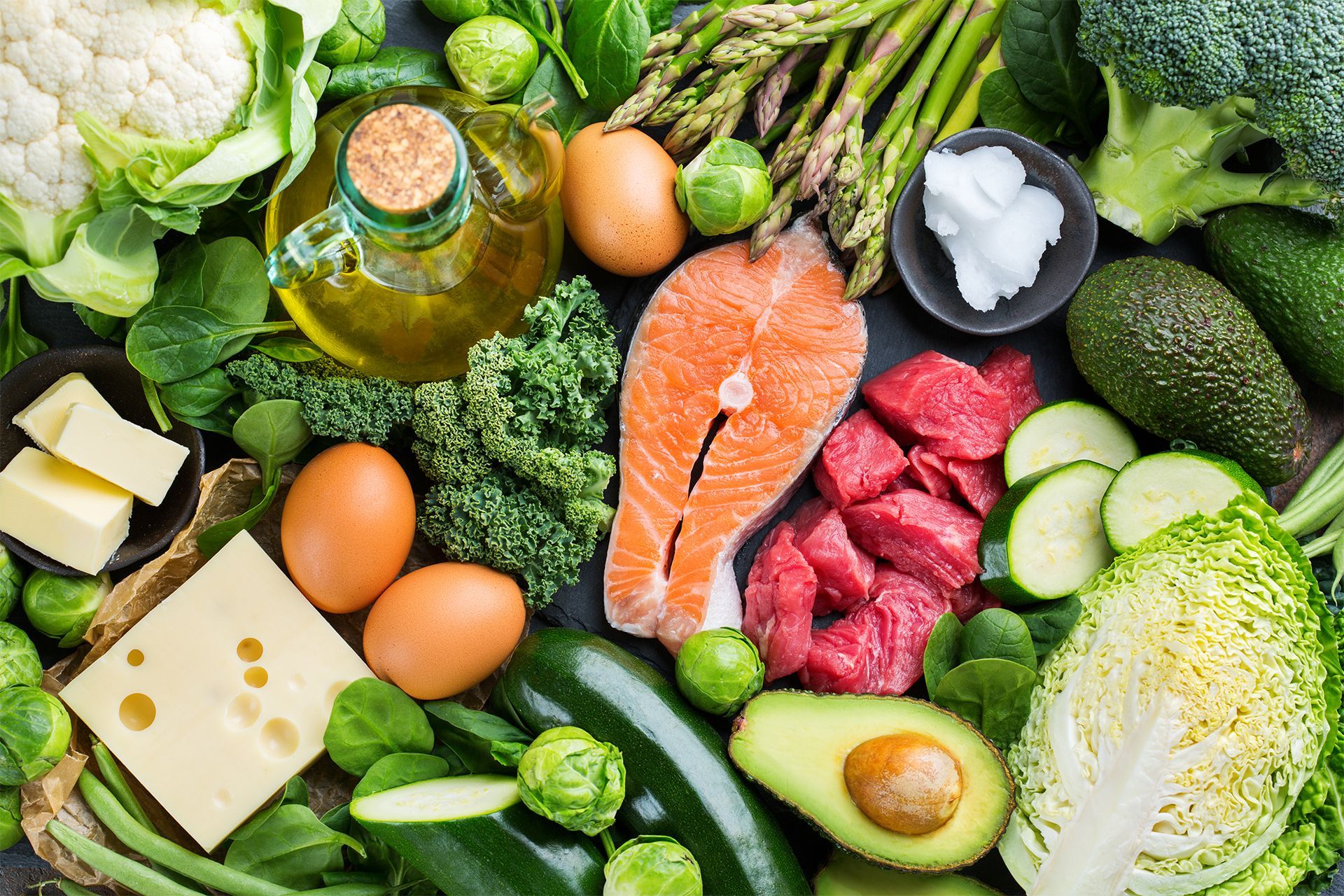 Assorted fresh vegetables, eggs, cheese, salmon, and meat on a dark background. Assorted fresh vegetables, eggs, cheese, salmon, and meat on a dark background.