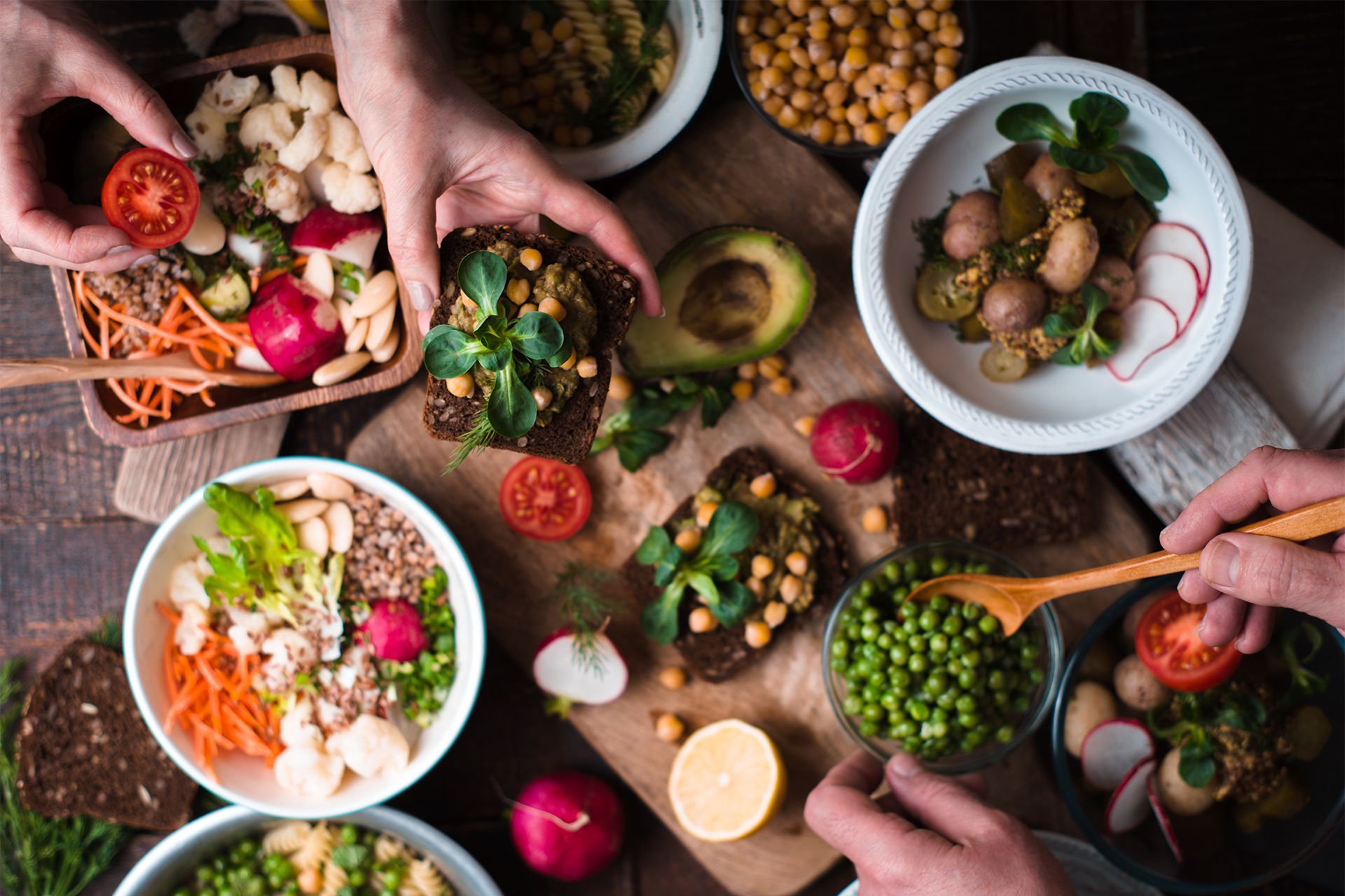 Hands preparing colorful salad bowls with vegetables and fruit on a rustic table. Hands preparing colorful salad bowls with vegetables and fruit on a rustic table.