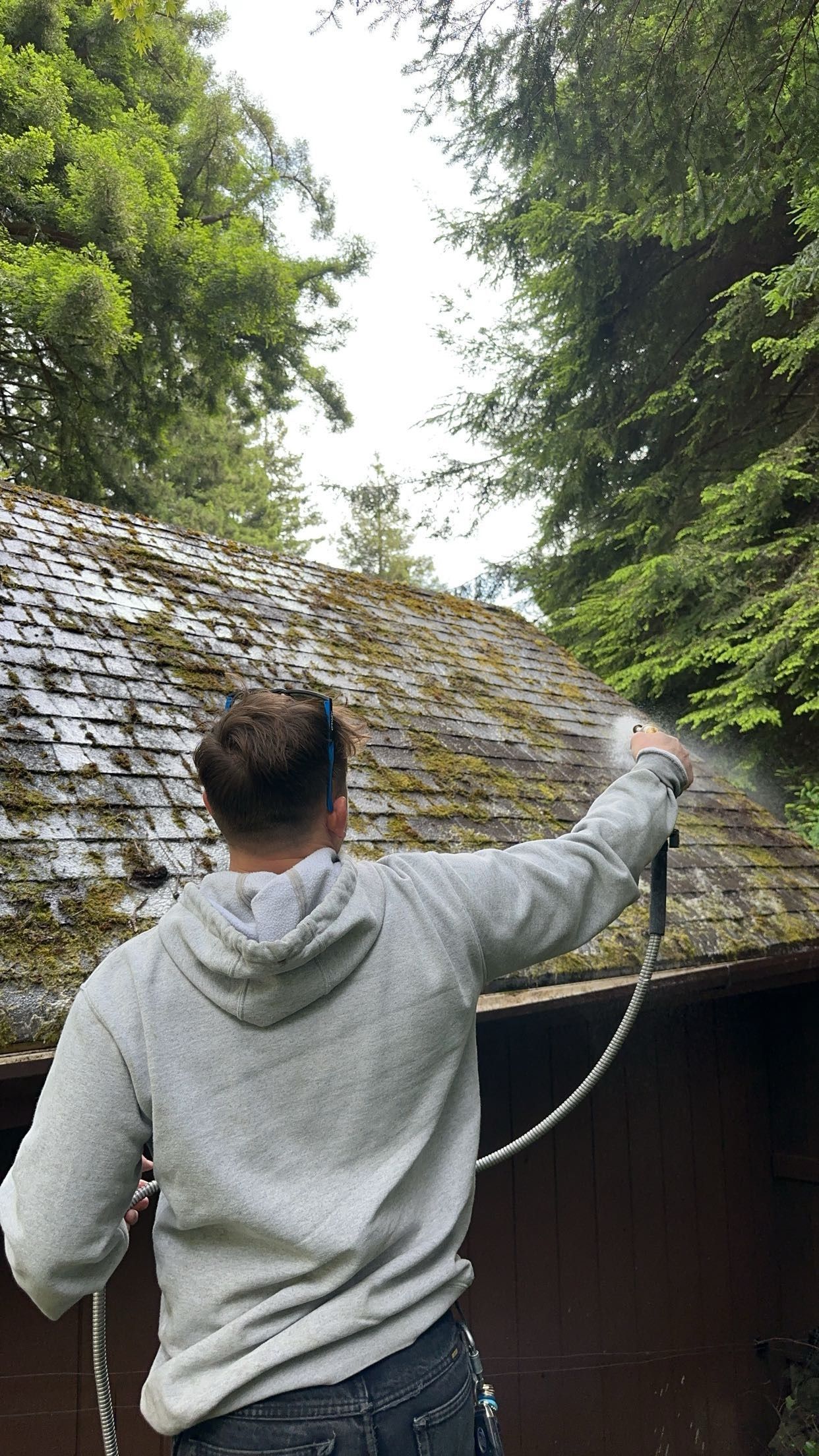 A man is cleaning a roof with a high pressure washer.