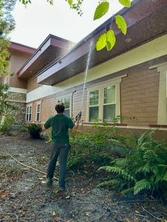 A man is spraying water on the side of a building.