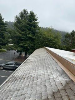 A roof with a lot of shingles on it and trees in the background.