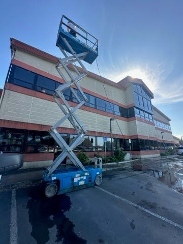 A scissor lift is cleaning the side of a large building.