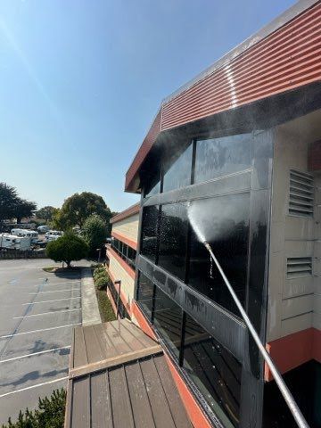 A person is cleaning the windows of a building with a high pressure washer.
