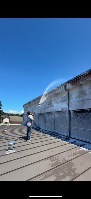 A man is spraying water on the side of a building.