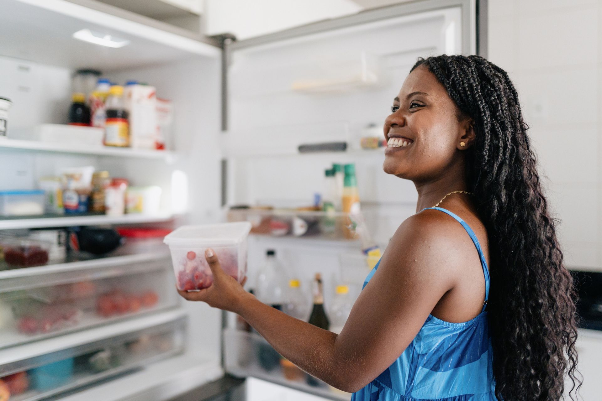 Woman reaches into a refrigerator in a modern kitchen.
