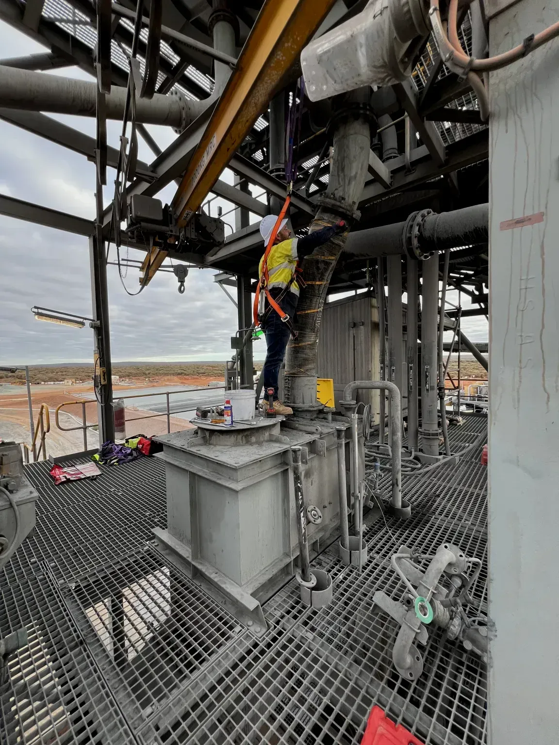 A man is standing on top of a metal platform in a factory.