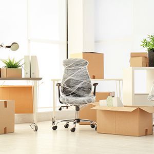 Office Chair Is Wrapped In Plastic And Surrounded By Cardboard Boxes