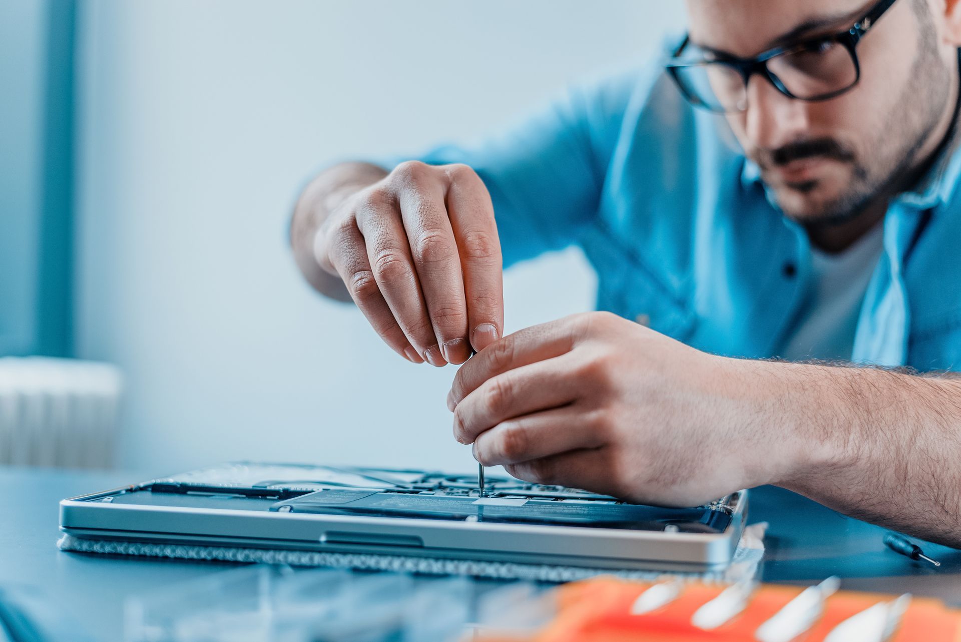 Technician repairing a laptop with a screwdriver.