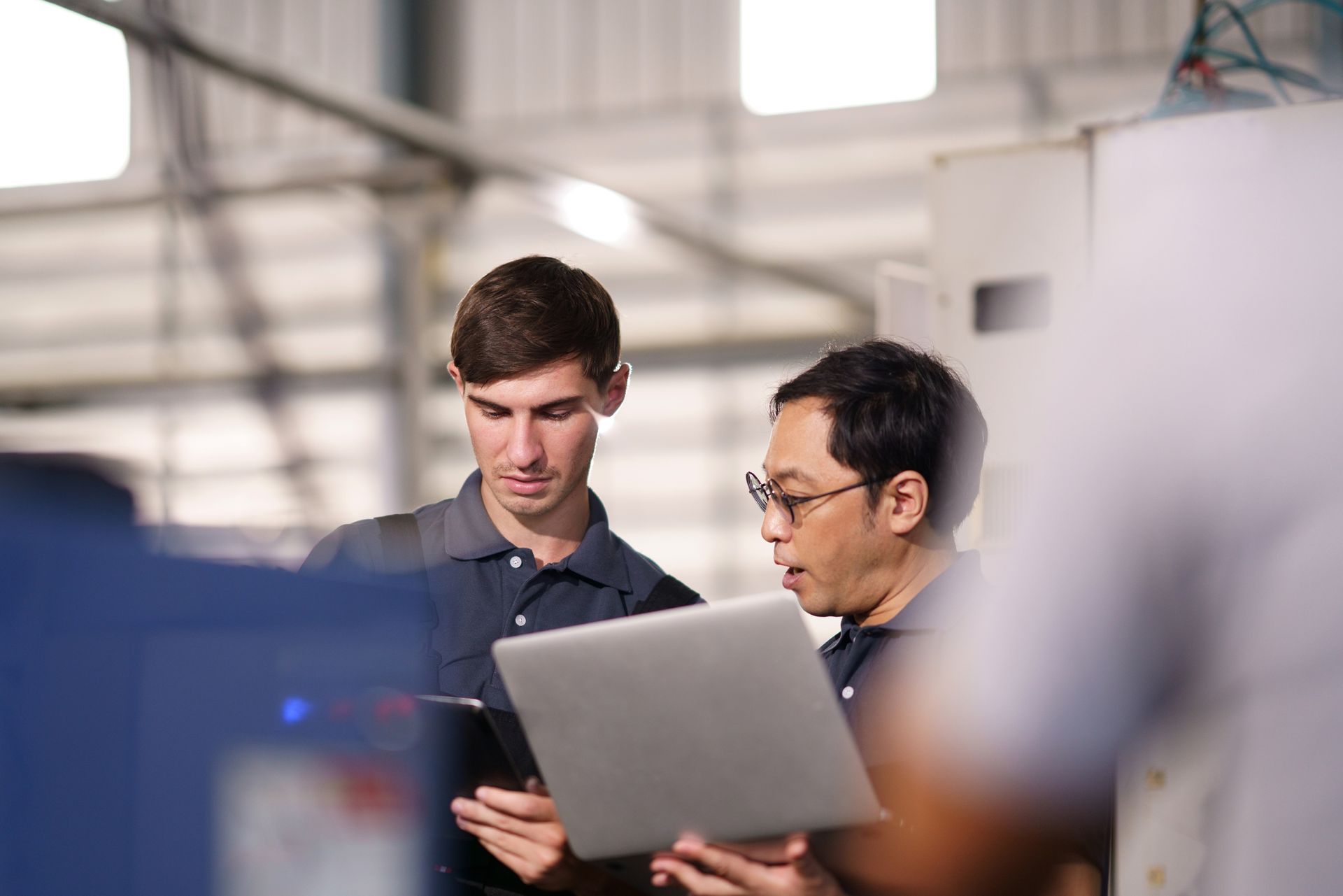 IT support technicians inspecting machine at manufacturing sites.