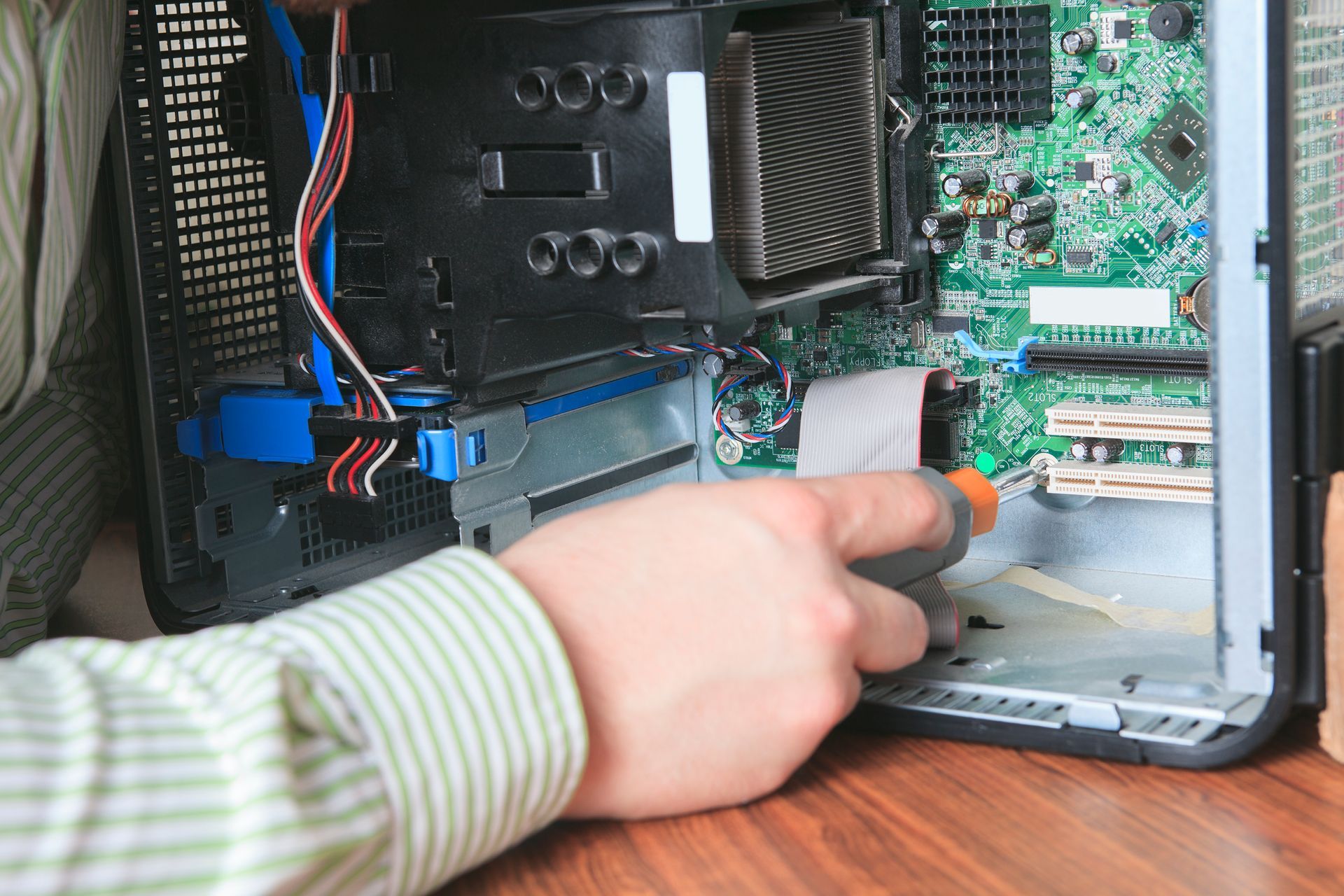 A person is working on a computer with a screwdriver.