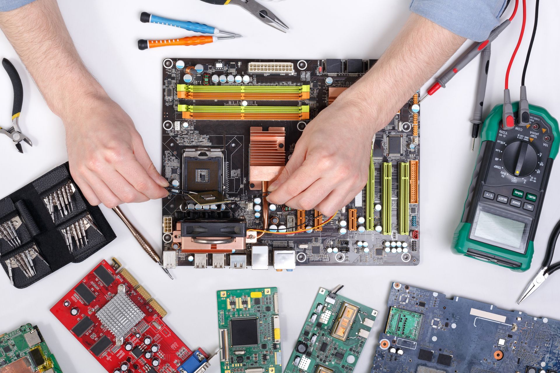 A person is working on a motherboard with tools.