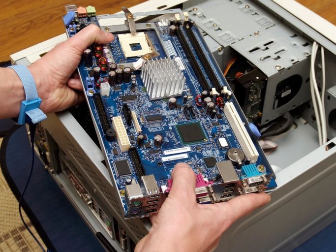 A person is holding a computer motherboard in their hands.