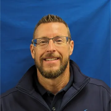 A man with glasses and a beard is smiling for the camera