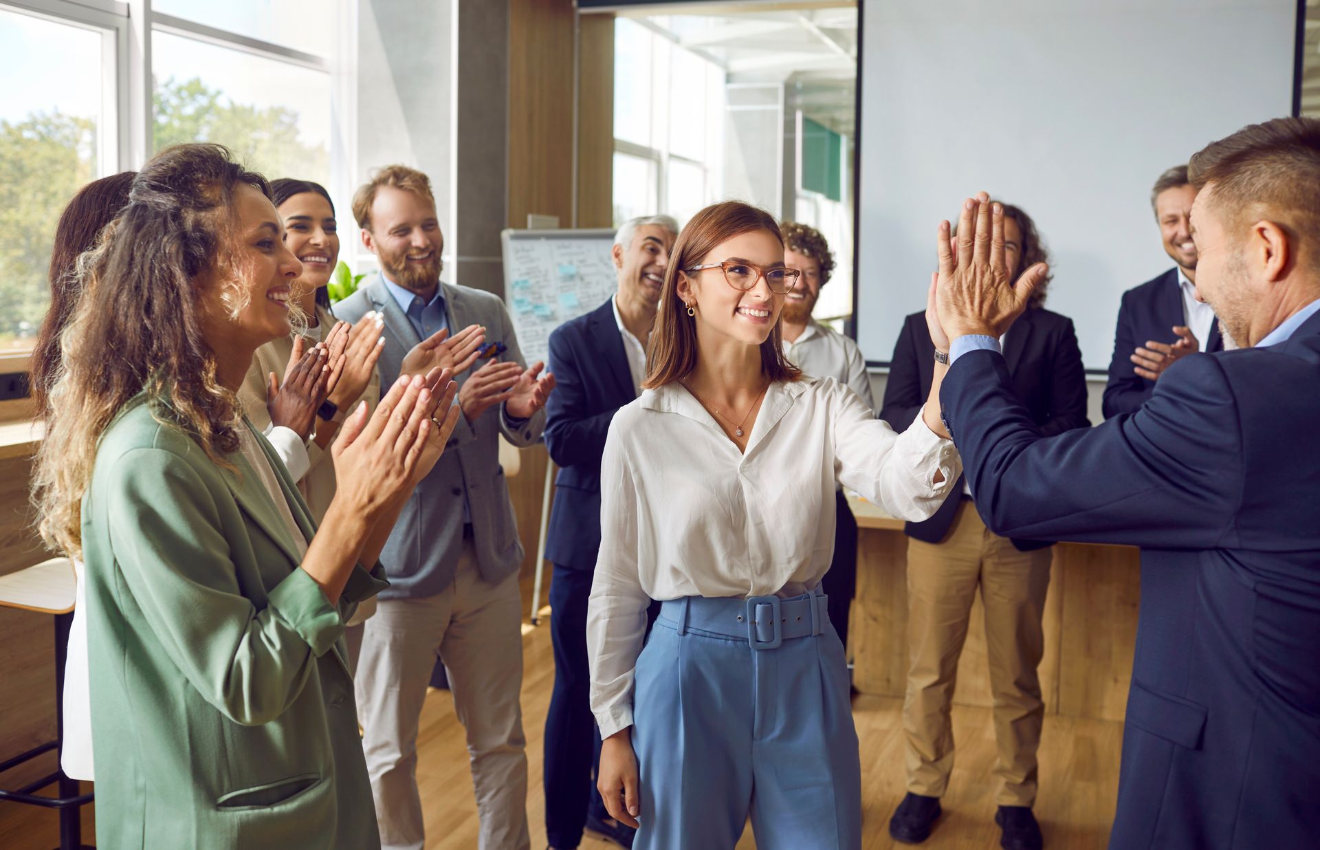 A group of people are giving each other a high five in an office.