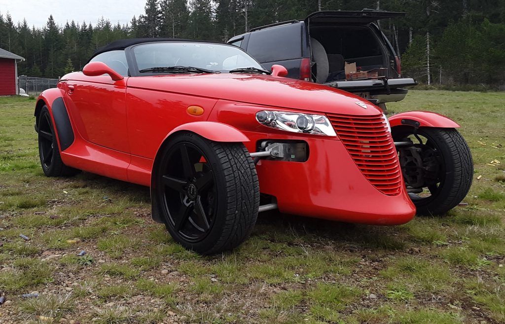 A red sports car is parked in a grassy field.