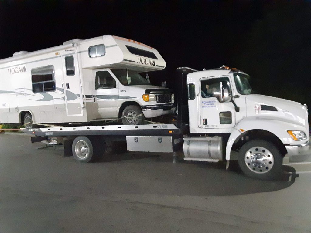 A rv is being towed by a tow truck.