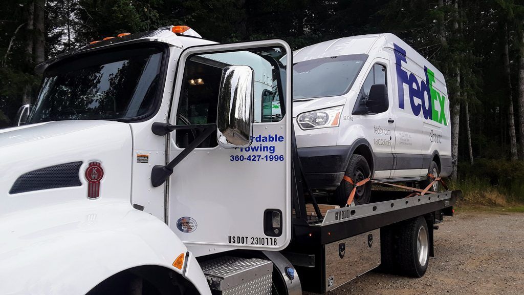 A fedex van is being towed by a tow truck.