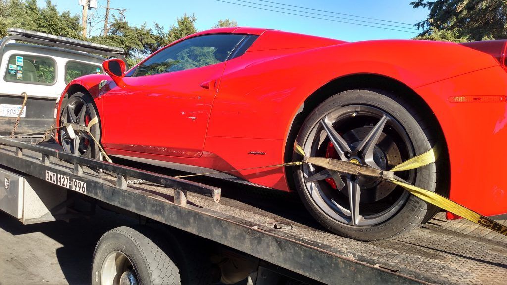 A red sports car is sitting on top of a tow truck.
