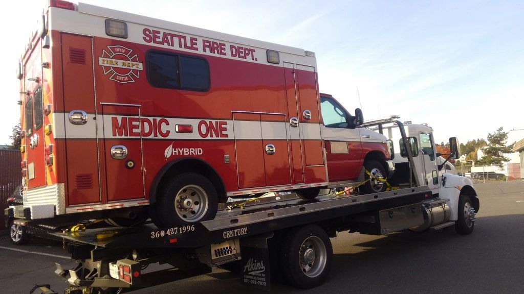A seattle fire department ambulance is being towed by a tow truck