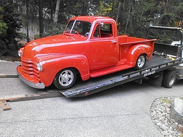 A red truck is being towed by a tow truck