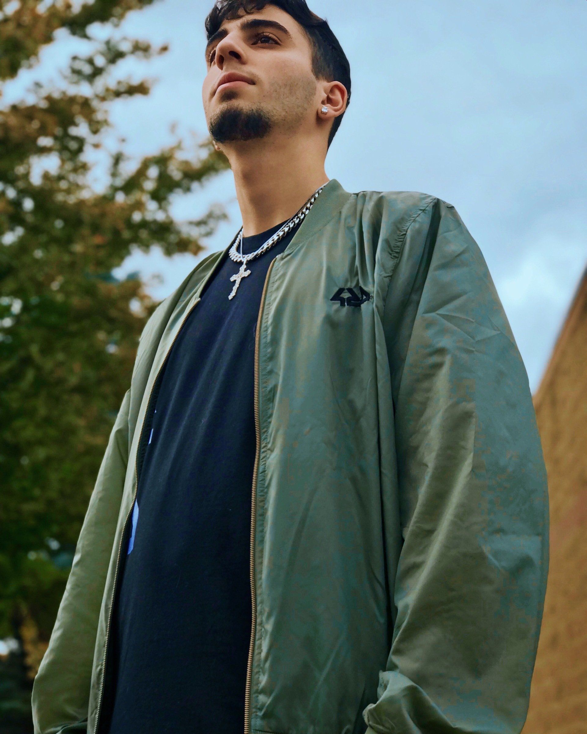 A man wearing a green bomber jacket and a black shirt