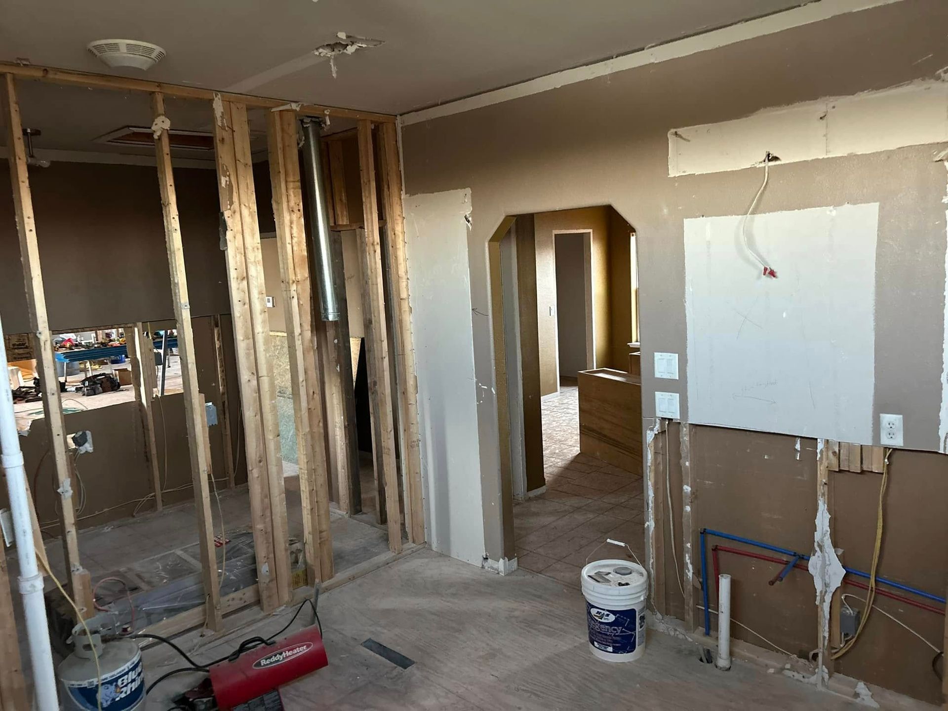 Interior construction, wooden framing, exposed pipes, drywall, and partially demolished walls.