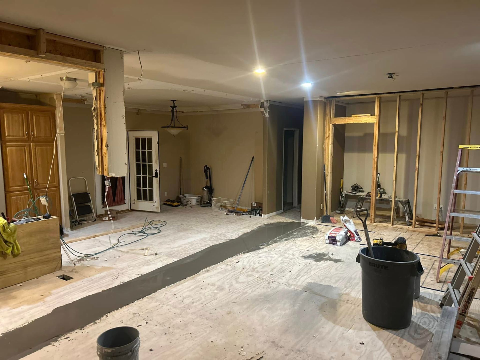 Interior room under renovation; exposed framing, debris, and tools scattered.