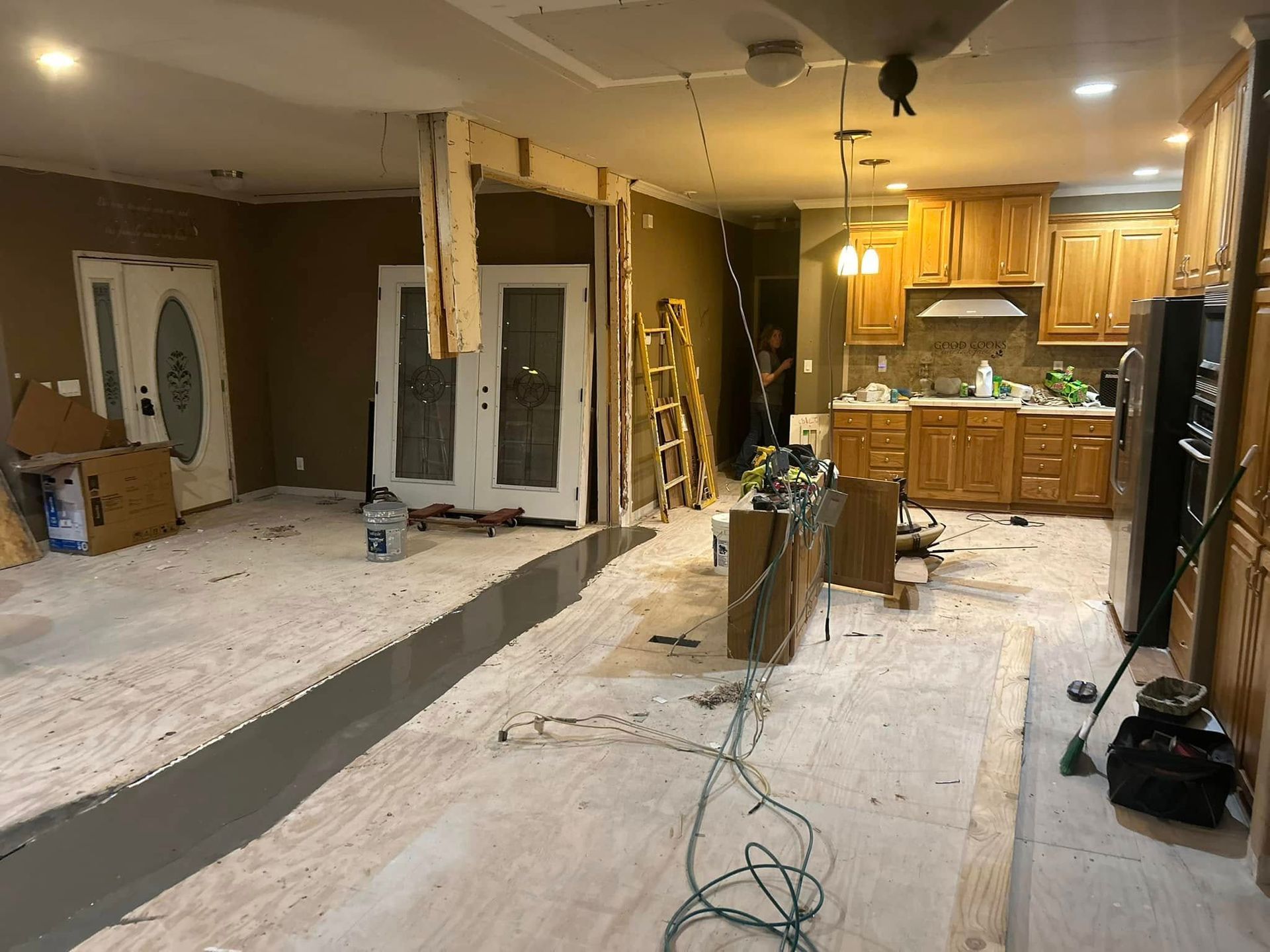 Interior home renovation with exposed flooring, kitchen in the background.