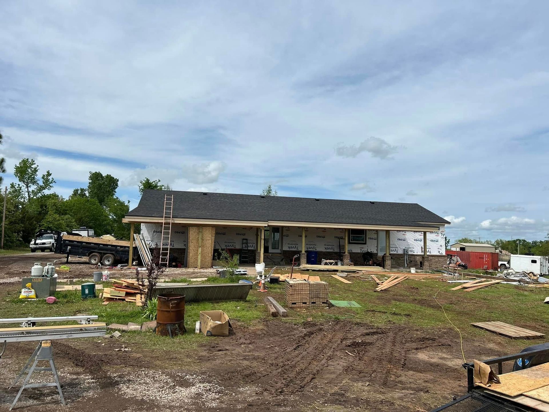 Construction site with a partially built, single-story building; dirt, wood, and tools are visible.