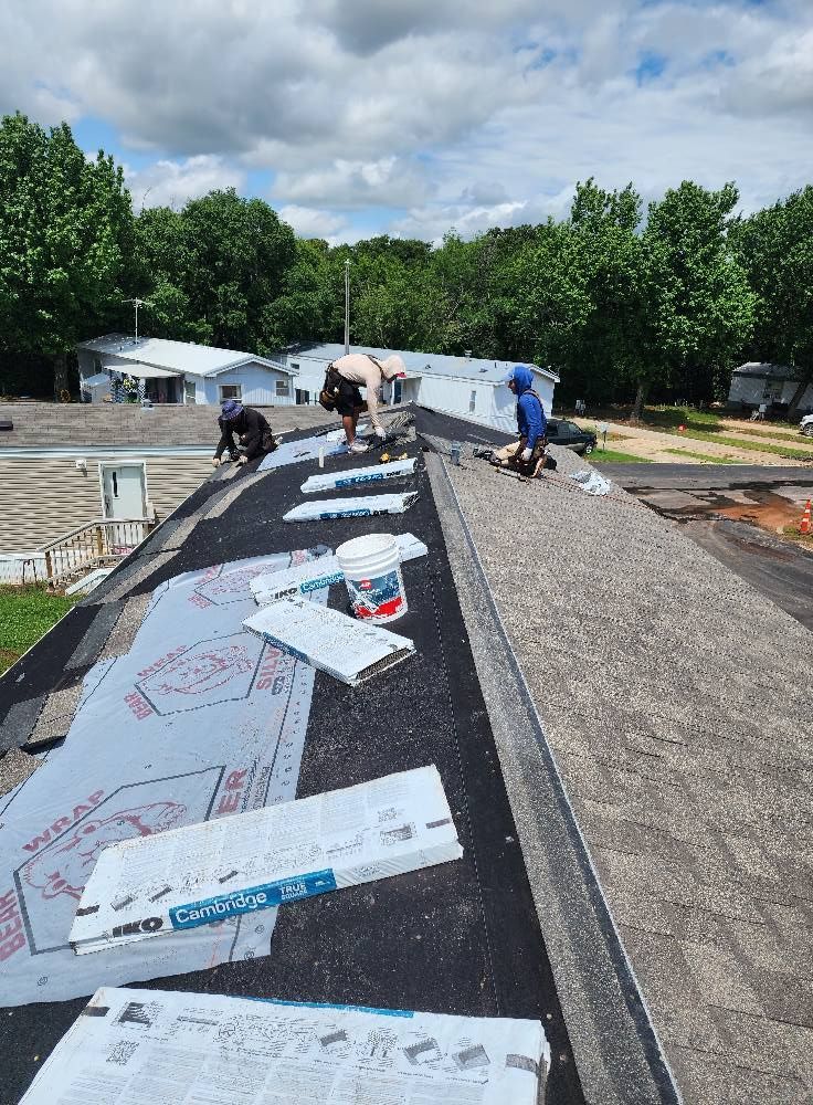 Roofers installing roofing material on a flat roof, sunny day.