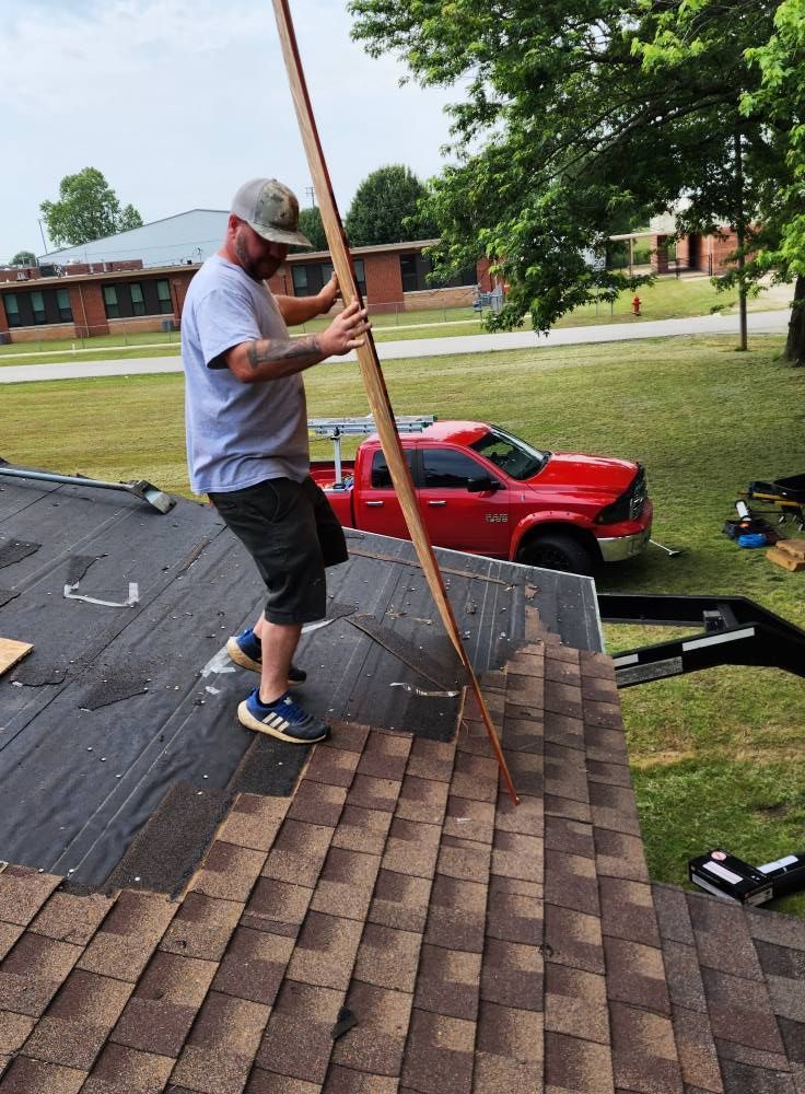 Man on a roof installing shingles. Red truck in the background.
