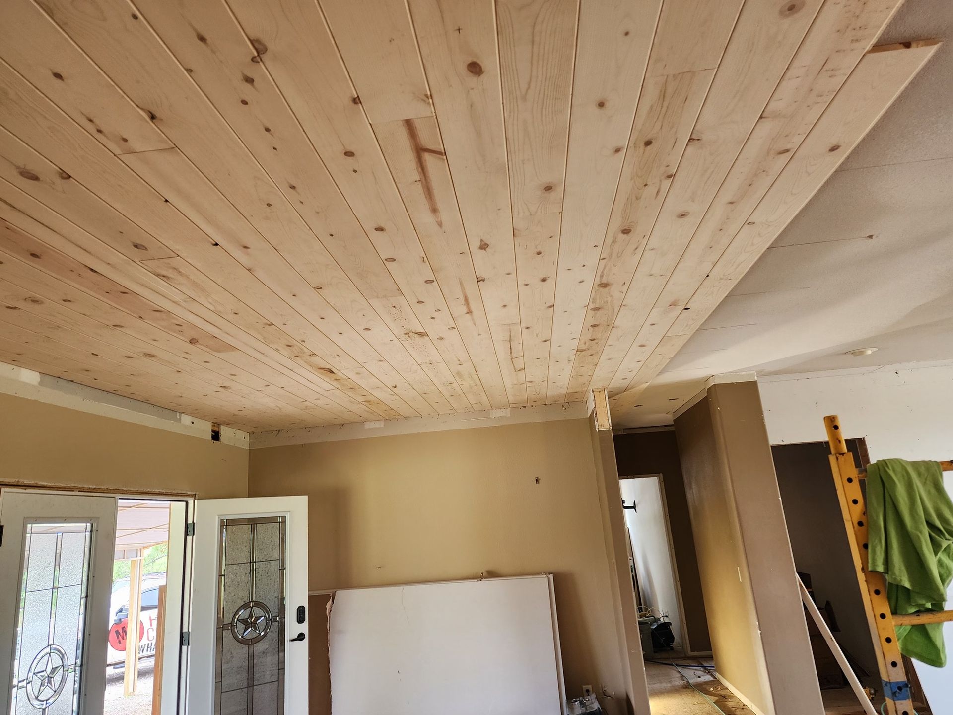 Wooden planks installed on a ceiling in a room under renovation.