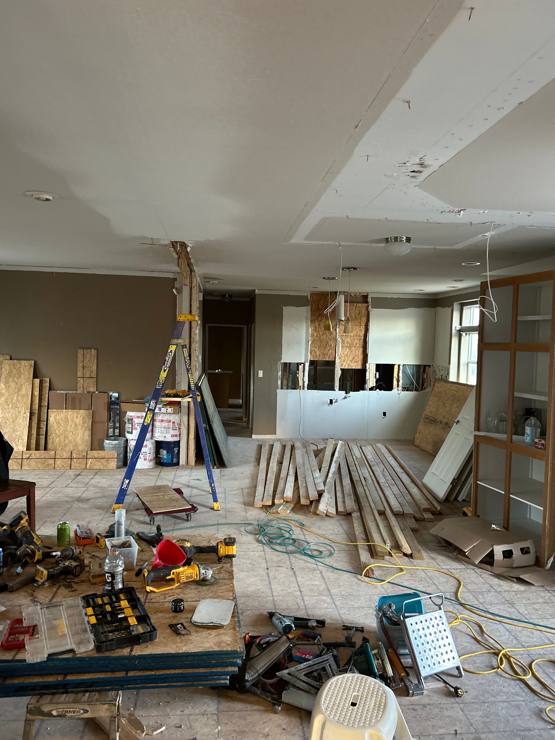Roofers replacing plywood on a flat roof, using a leaf blower. Workers are visible.