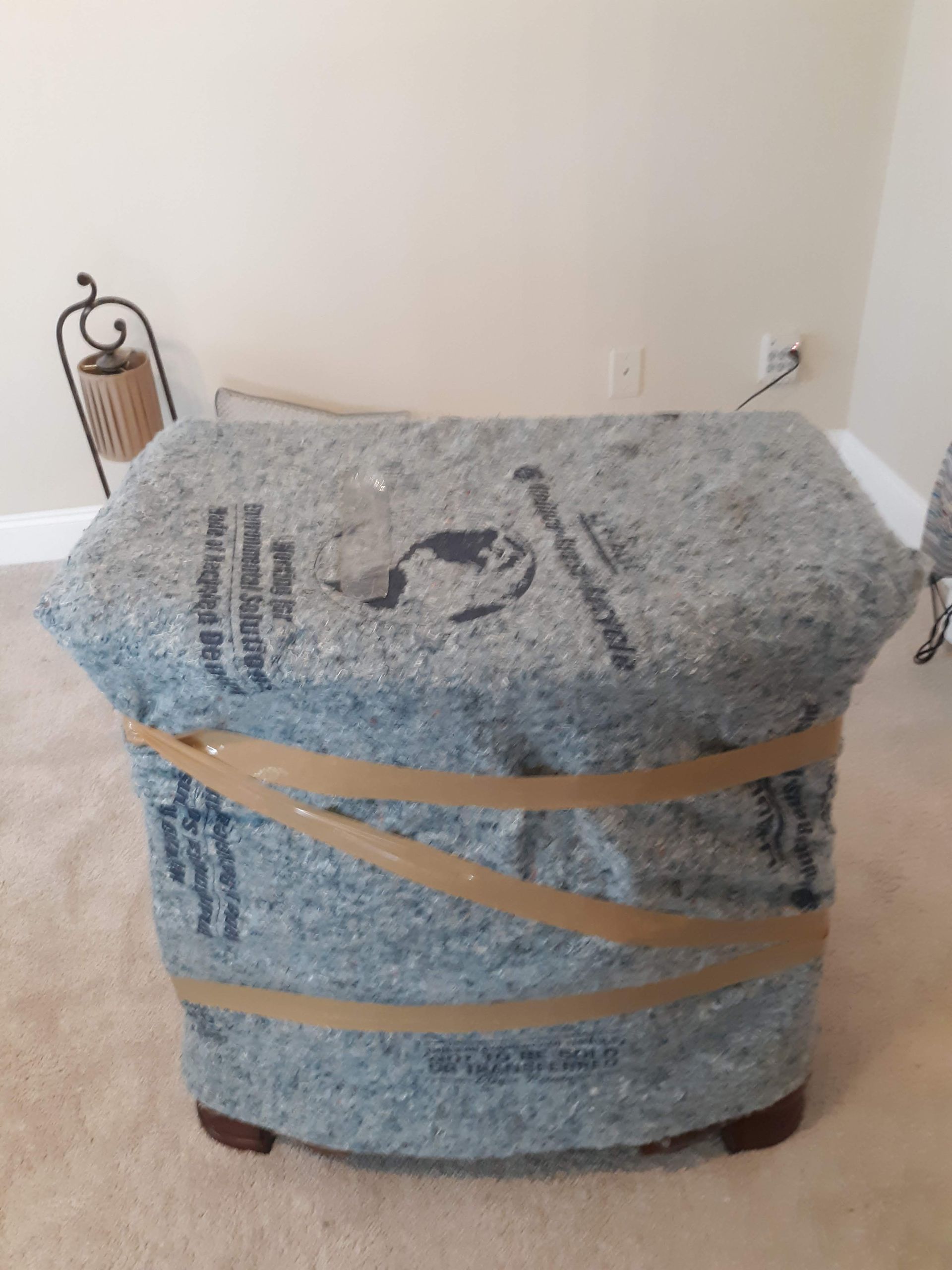 A chair is wrapped in plastic and tape in a living room.