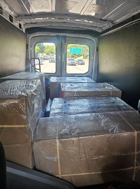 The inside of a van filled with boxes wrapped in plastic.