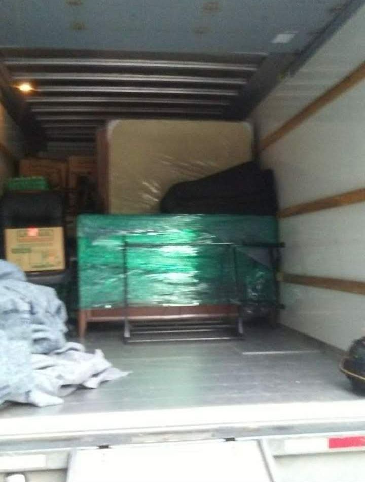 The inside of a moving truck filled with furniture and boxes