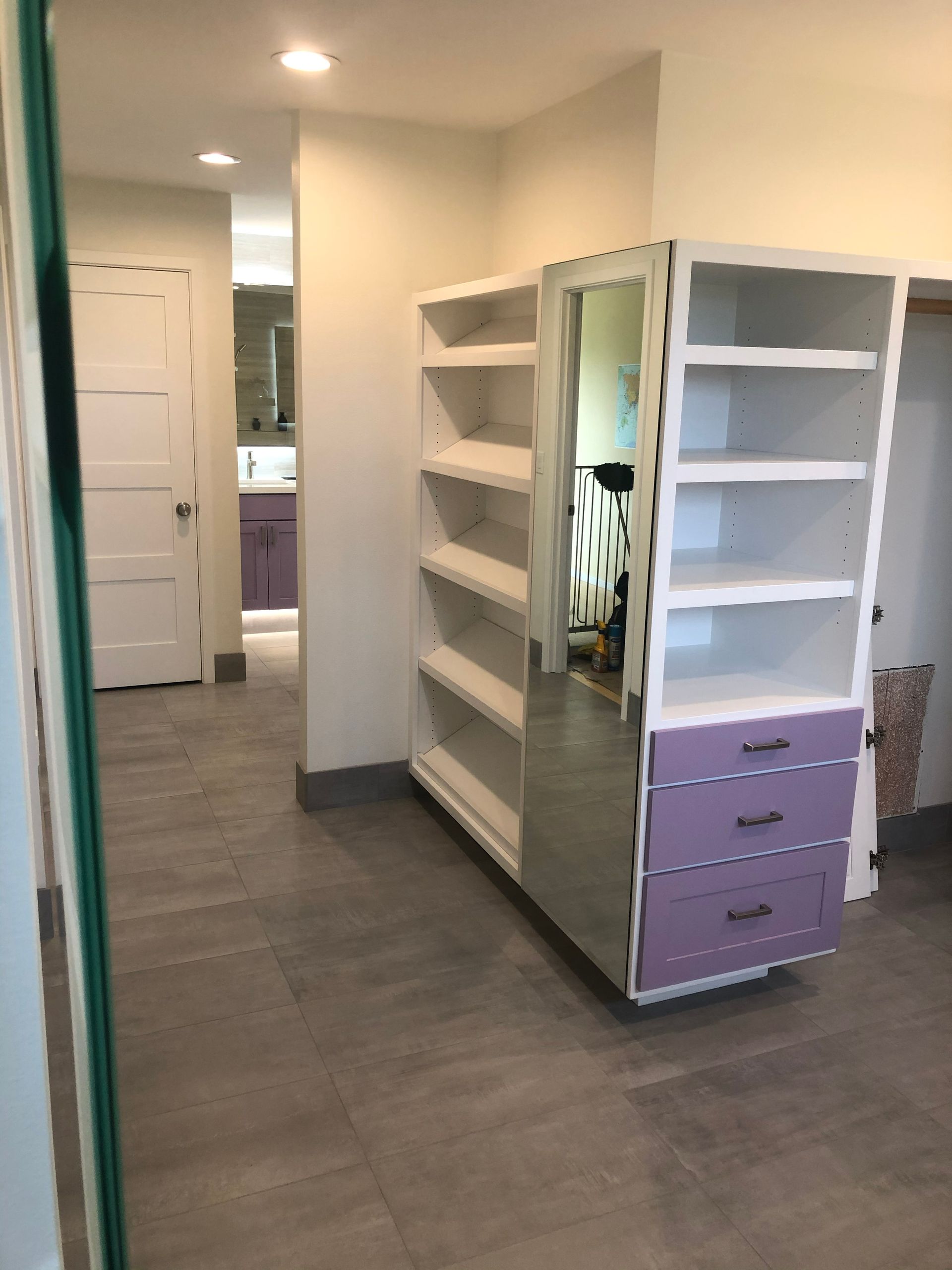 Hallway with white shelving units and a lavender drawer cabinet in a bright room