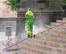 A person is cleaning a tiled roof with a high pressure washer.