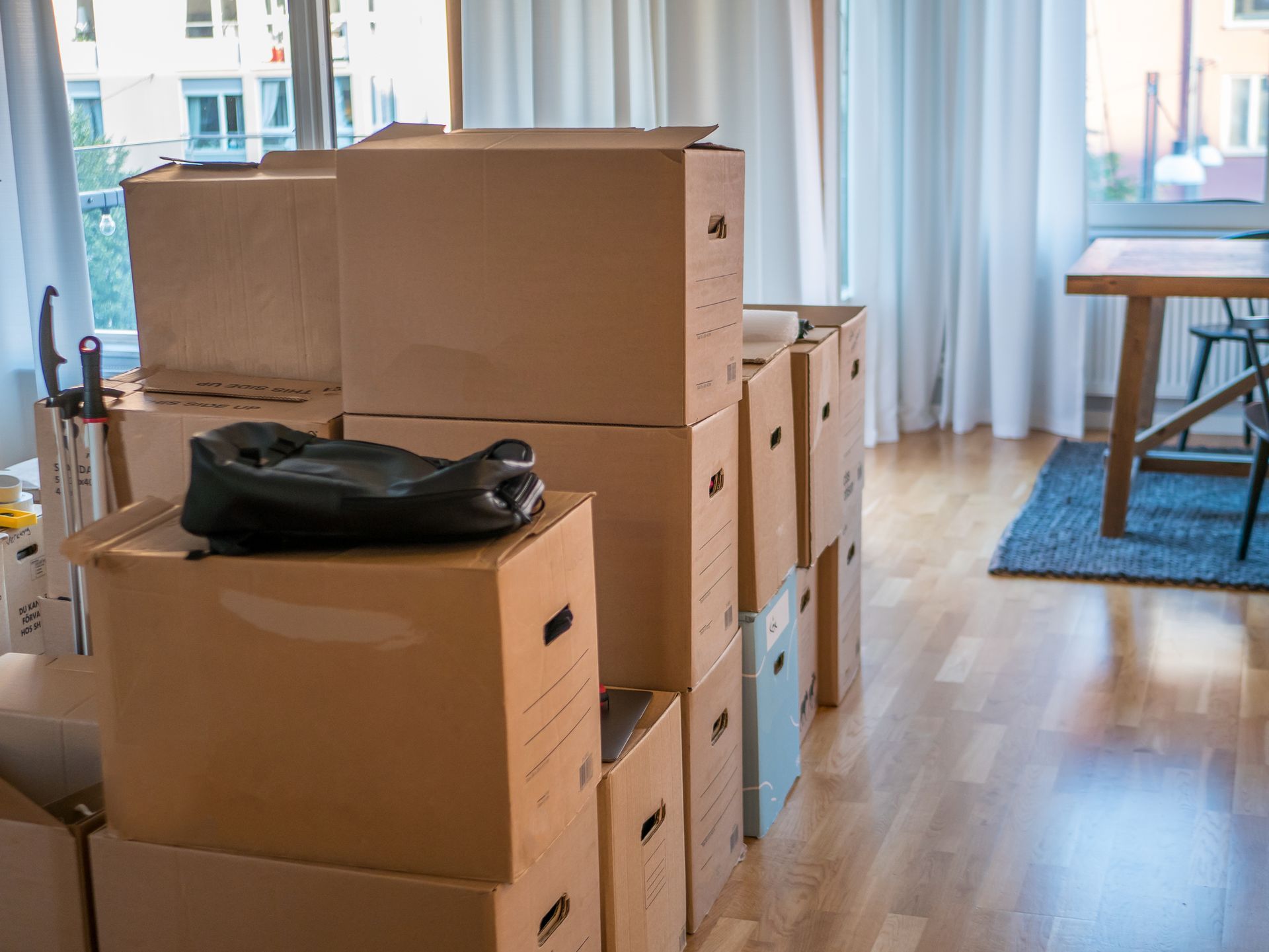 Cardboard boxes stacked in a room, ready for moving; a shoe rests on top.